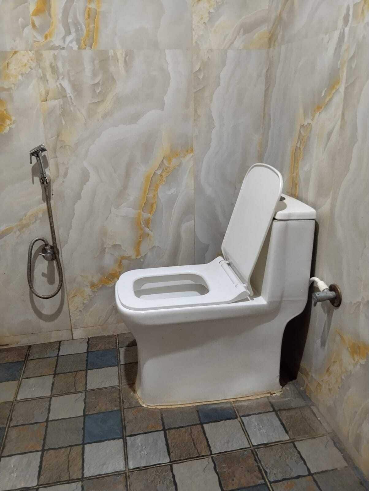 Un baño con inodoro, ducha y suelo de baldosas.