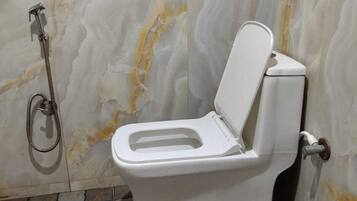 Un baño con inodoro, ducha y suelo de baldosas.