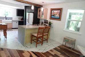 A modern kitchen with a central island, wooden chairs, and a dining table. - Earthy with a Pop of Bling House Nestled in beautiful Jupiter Farms, FL. (Jupiter)