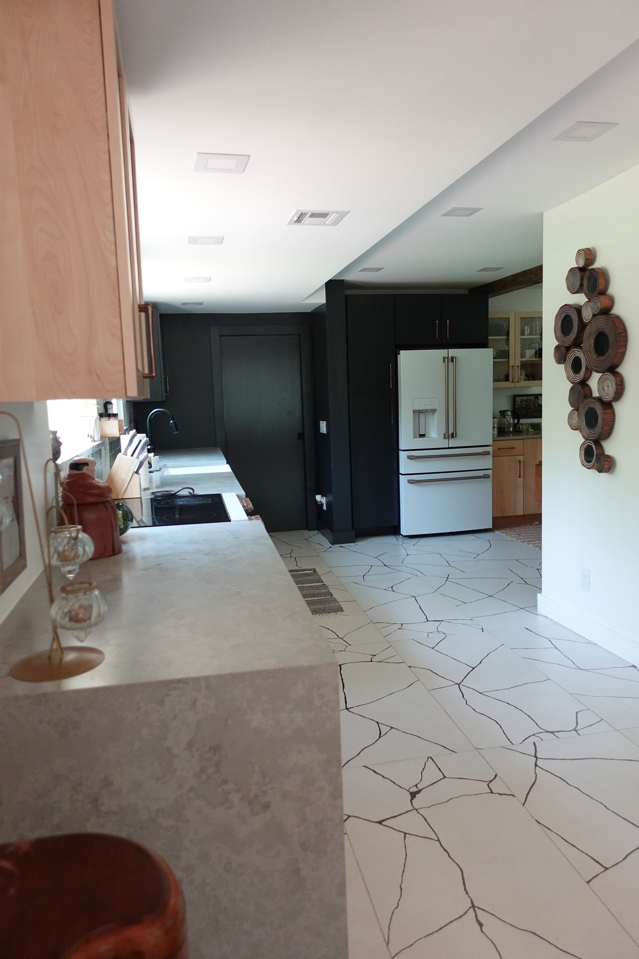 A modern kitchen with a central island, dark cabinetry, and a patterned floor.