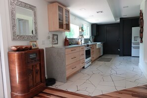 A modern kitchen with wooden cabinets, a built-in oven, and a tiled floor.