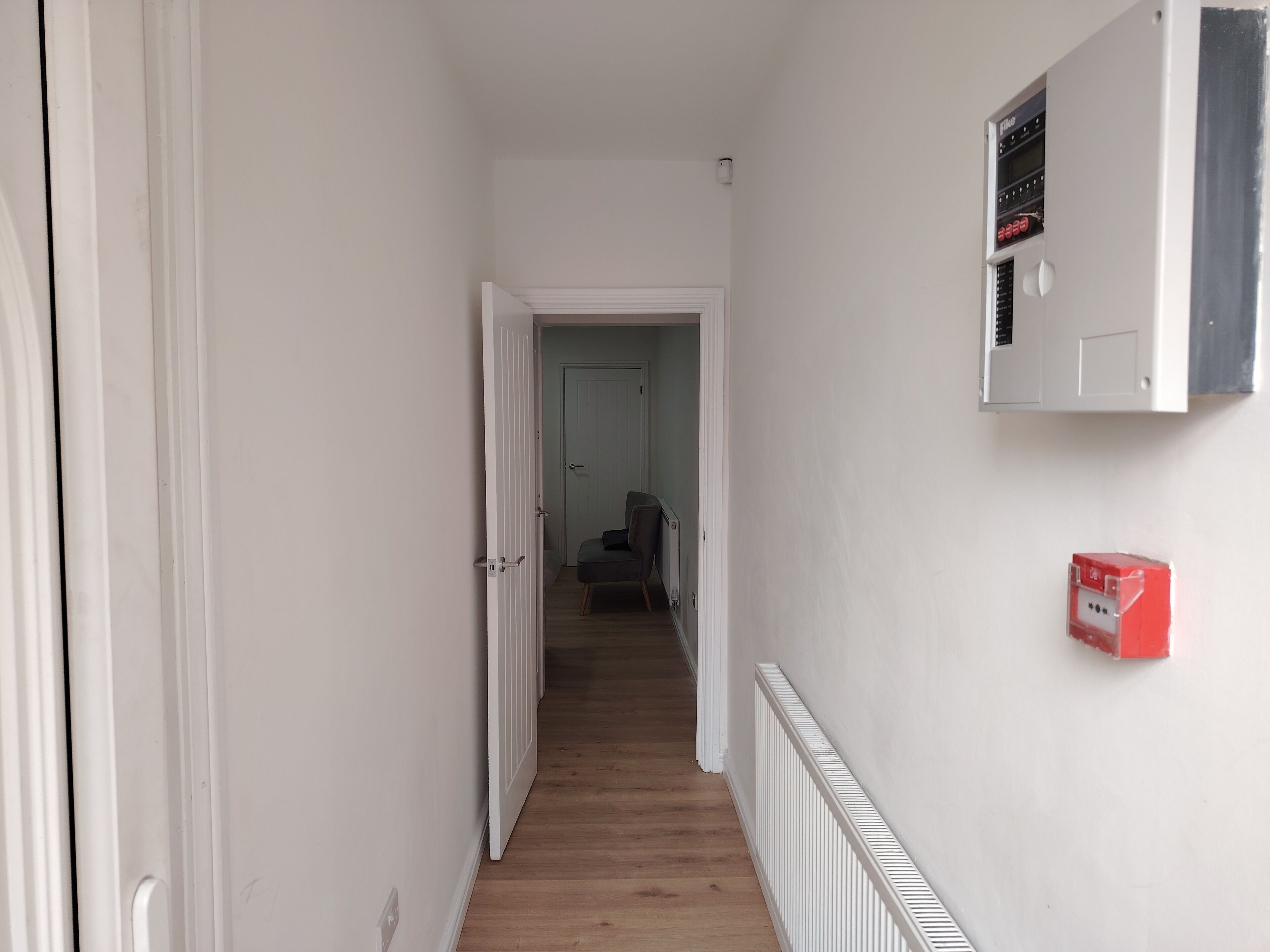 A hallway with a radiator, a door, and a red fire alarm box.