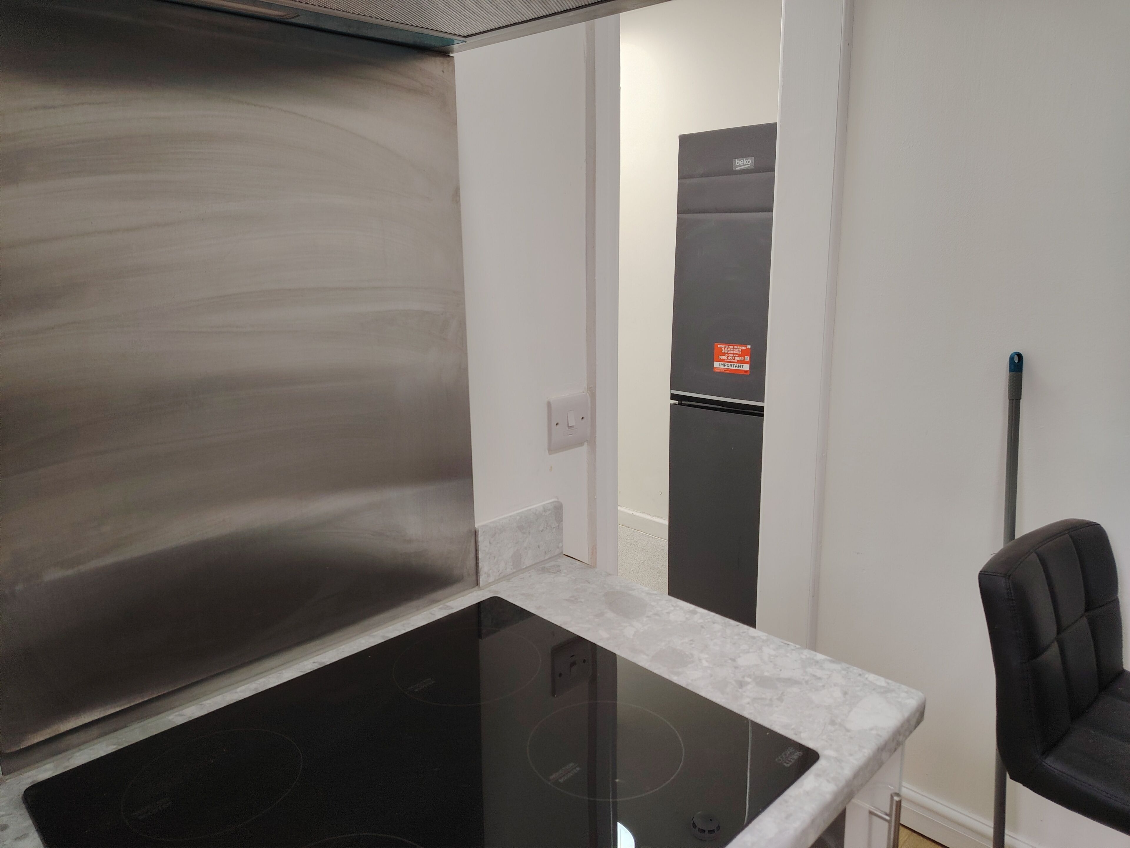 A kitchen with a black induction cooktop, a white countertop, and a black chair.