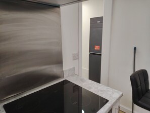 A kitchen with a black induction cooktop, a white countertop, and a black chair. - Modern 3‑Bed Home Near Dudley Zoo, Black Country Museum & Russell Hall Hospital (Dudley)