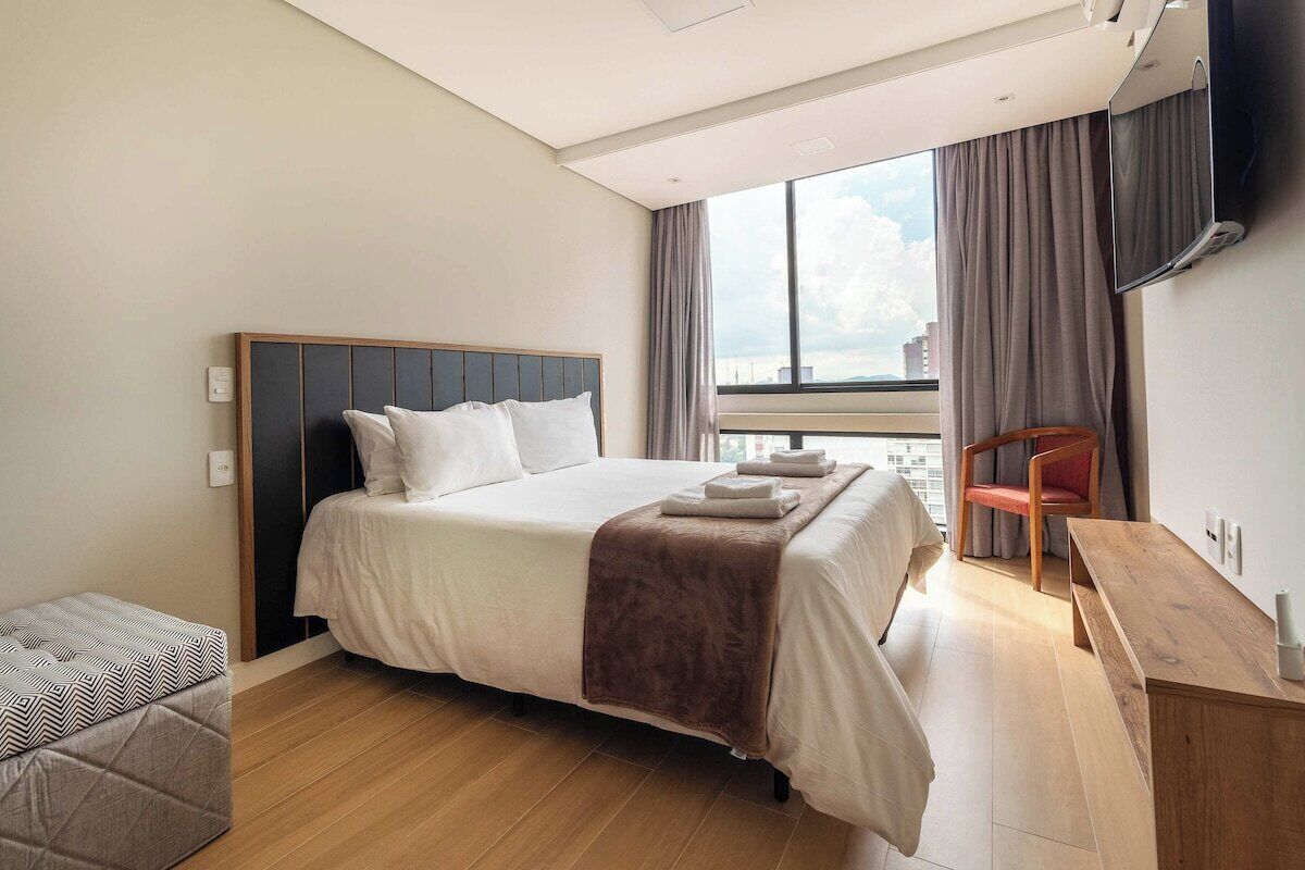 Una camera d'hotel moderna con un letto grande, un piccolo angolo relax e vista sulla città.