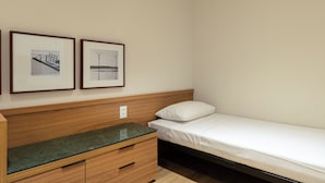 A single bed with a wooden headboard, a small bedside table with drawers, and two framed pictures on the wall. - Mercurio by Bhomy (São Paulo)