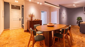 A modern dining area with a wooden table and chairs, a vase of flowers, and a geometric wall art piece. - Mercurio by Bhomy (São Paulo)