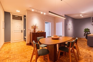 Ein moderner Essbereich mit Holztisch und -stühlen, einer Blumenvase und einem geometrischen Wandbild.