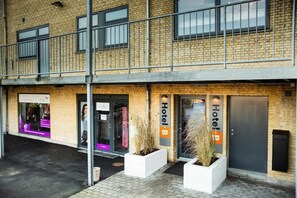 A hotel with a brick facade, large windows, and a sign indicating the name.