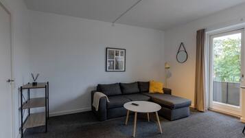 A modern living room with a grey sofa, a small round table, and a picture frame on the wall.