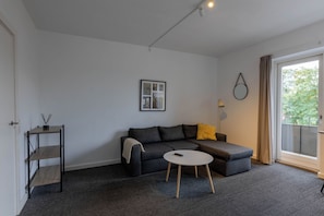 A modern living room with a grey sofa, a small round table, and a picture frame on the wall.
