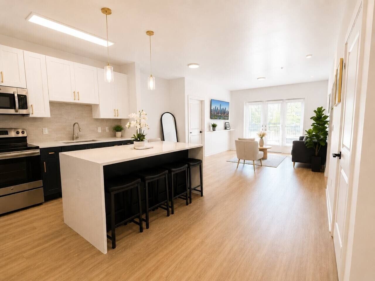 A modern kitchen with white cabinets, a central island with bar stools, stainless steel appliances, and pendant lighting.