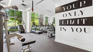 A gym with treadmills, a weight bench, and a motivational quote on the wall.