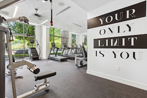 A gym with treadmills, a weight bench, and a motivational quote on the wall. - Luxury 2BR Near Uptown | Pool, Gym, BBQ (Charlotte)
