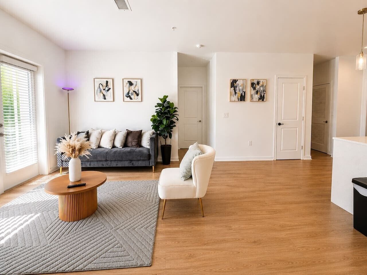 Un salon spacieux comprenant un canapé, un fauteuil, une table basse et des œuvres d’art accrochées aux murs.