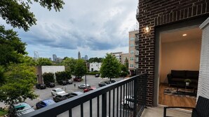 Een balkon met uitzicht op een parkeerplaats en stadsgebouwen.