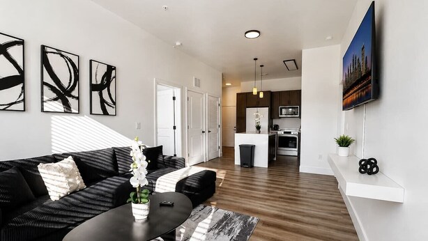 Een moderne woonkamer met een zwarte bank, een salontafel en abstracte kunst aan de wand.