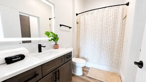 Een badkamer met een witte wasbak, donkere kastjes, een toilet en een douchegordijn.