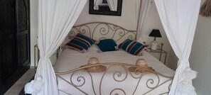 Ein Himmelbett mit Baldachin, Kissen und einem Nachttisch mit Lampe.