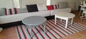 Ein Wohnzimmer mit einer Couch, zwei runden Tischen und einem Streifen Teppich.