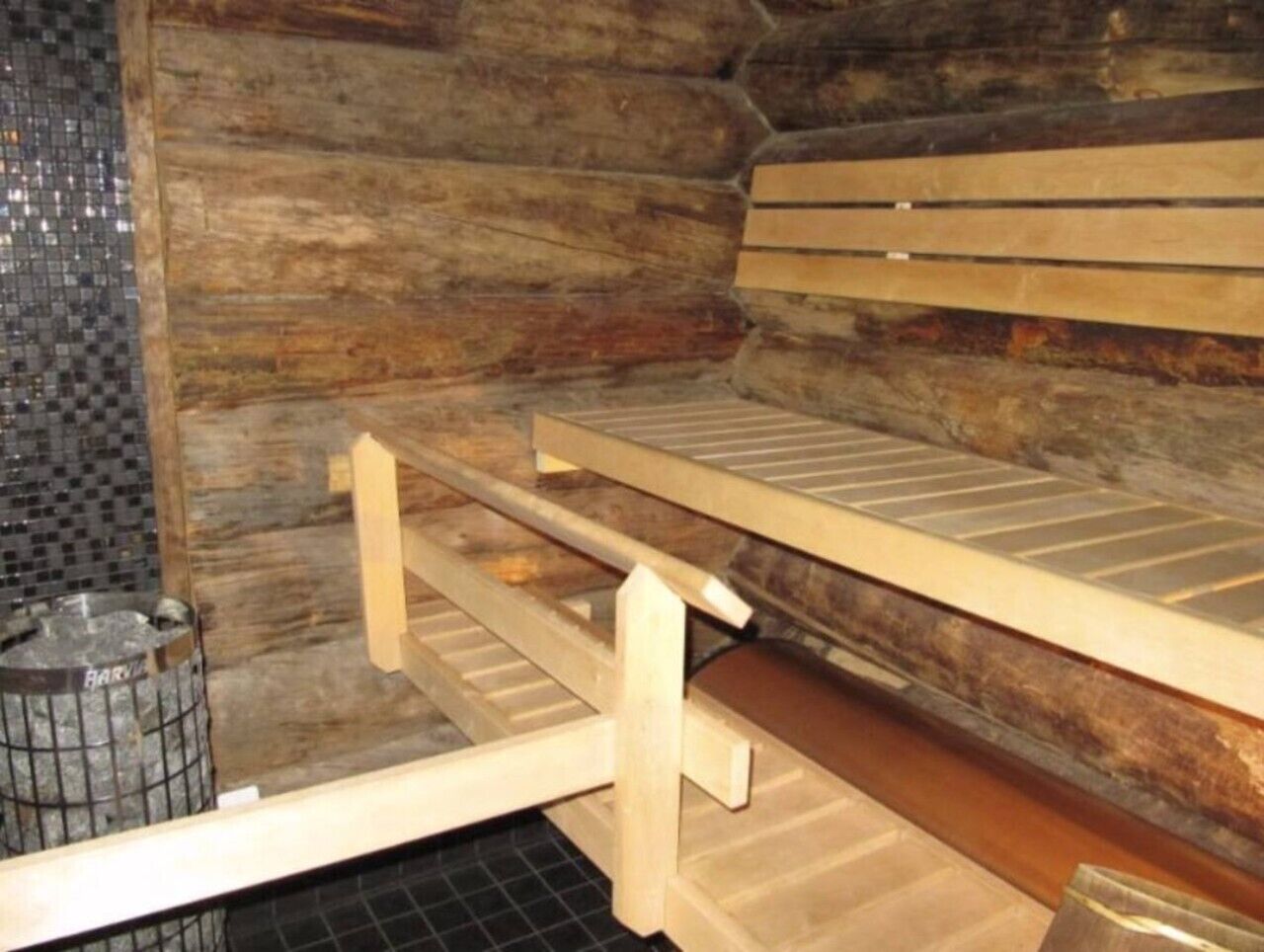 Een sauna met houten banken en een betegelde wand.