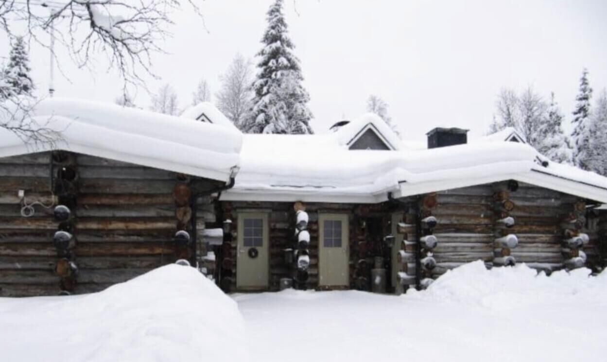 Una cabana de fusta amb un sostre cobert de neu, parets de fusta i un porxo.