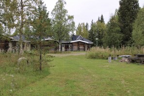 Eine Blockhütte mit Veranda, umgeben von einer Wiese und Bäumen.