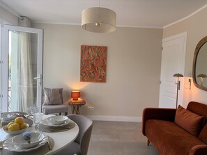 A dining area with a round table set for four, a sofa, a lamp, and a painting on the wall. - Villa Orange (La Croix-Valmer)