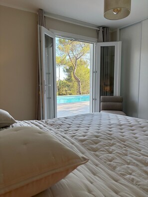 A bedroom with a bed, a view of a pool, and a door leading outside. - Villa Orange (La Croix-Valmer)