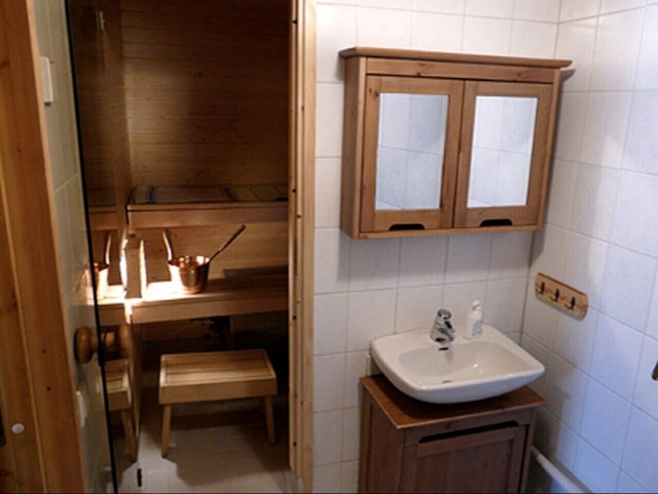 Ein kleines Badezimmer mit einem Holzkosmetikschrank, einem Waschbecken und einem Schrank über dem Spiegel.