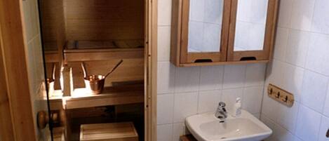 Ein kleines Badezimmer mit einem Holzkosmetikschrank, einem Waschbecken und einem Schrank über dem Spiegel.