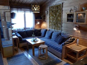 Ein gemütliches Cabin-Interieur mit einer Couch, einem kleinen Tisch, einem Hocker und einer Lampe.