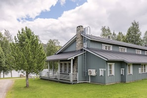 A two-story house with a stone chimney, a covered porch, and a large window. - Kivanta F 27 | Ruka Lakeside Chalet for 10 | Sauna (Ruka)