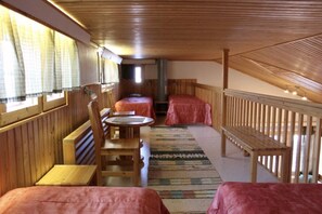 Ein Zimmer mit Holzwänden und einer geneigten Decke, mit einem Bett, einem Tisch und einer Bank.
