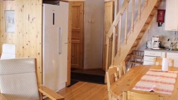 Un interior de madera con una mesa de comedor, sillas, una escalera y una zona de cocina.