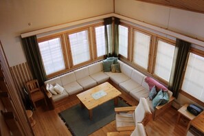 Una habitación acogedora con un amplio sofá modular, una mesa de centro de madera y una ventana con persianas.