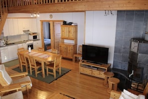 Ein gemütliches Interieur mit einem Holzesstisch, Stühlen, einem Fernseher und einem Kamin.