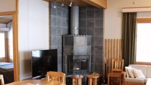 Un interior acogedor con una mesa de comedor de madera, sillas, chimenea y televisor.