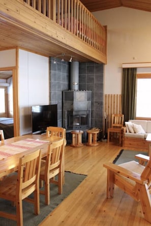 A cozy interior with a wooden dining table, chairs, a fireplace, and a television. - Kivanta F 27 | Ruka Lakeside Chalet for 10 | Sauna (Ruka)