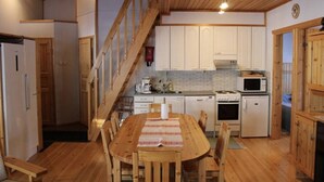 Un interior de madera con cocina, comedor y una escalera.