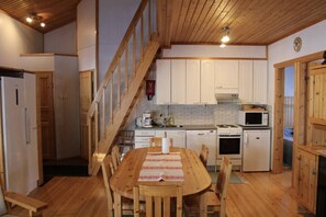 A wooden interior with a kitchen, dining area, and a staircase. - Kivanta F 27 | Ruka Lakeside Chalet for 10 | Sauna (Ruka)