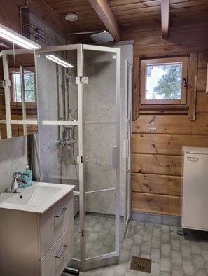 A bathroom with a shower enclosure, a sink with a mirror, and a window. - Maston Uuttu | Ruka Cabin Near Ski Trails & Slopes (Ruka)