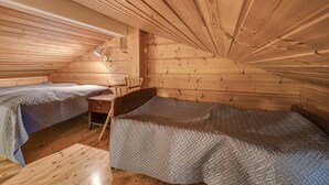 En stuga med två sängar, ett skrivbord och en stol.