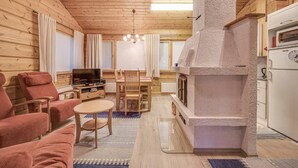 Ett mysigt vardagsrum med en öppen spis i sten, trämöbler och en tv.