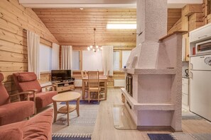Ein gemütliches Wohnzimmer mit Kamin aus Stein, Holzmöbeln und einem Fernseher.