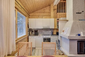 A compact kitchen with wooden cabinets, a stove, and a dishwasher. - Maston Uuttu | Ruka Cabin Near Ski Trails & Slopes (Ruka)