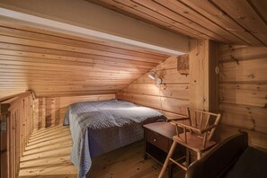 Een kleine houten kamer met een bed, een bureau en een stoel.