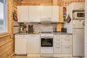 Eine kleine Küche mit weißen Schränken, einem Herd, einem Backofen und einer Mikrowelle.