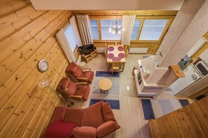 A cozy cabin interior with a wooden floor, a sofa, a dining table with a Mickey Mouse design, and a fireplace. - Maston Uuttu | Ruka Cabin Near Ski Trails & Slopes (Ruka)
