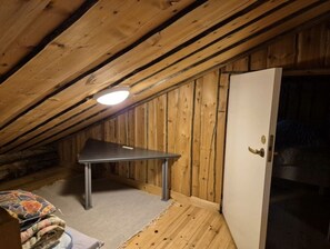 A small attic room with a table, a door, and a light fixture. - Kieruka C | Cozy Log Cabin | Sauna & Fireplace (Ruka)